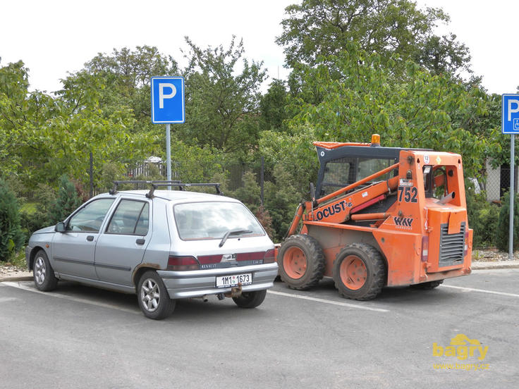 Smykem řízený nakladač Locust L 752 na parkovišti u benzinky