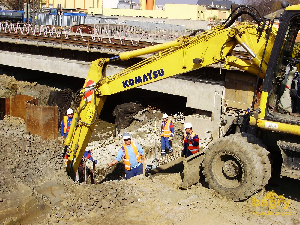 Kolové rypadlo Komatsu PW130 firmy Žvátora podává dělníkům suchý beton