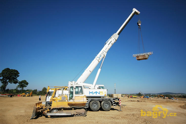 Pásový dozer Liebherr PR 712 Litronic firmy PSJ servis před autojeřábem téže značky firmy H.A.N.S. stavby