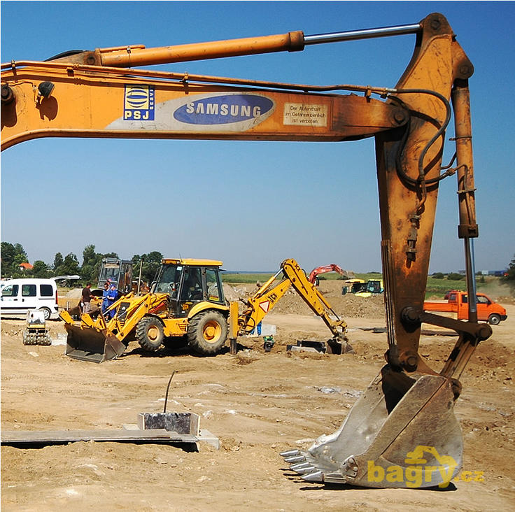 Podkop pásového rypadla Samsung SE210 LC, v pozadí rypadlonakladač JCB 3CX