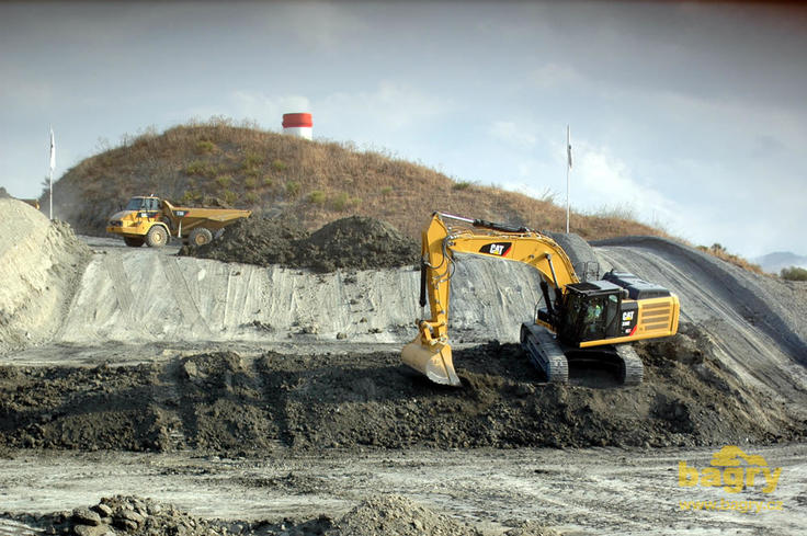 Kloubový dempr Caterpillar 730 přijíždí pod rypadlo Caterpillar 329E