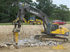 Pásové rypadlo Volvo EC360C L s bouracím kladivem. V pozadí rypadlonakladač Komatsu WB 93S