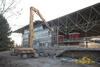 Demoliční rypadlo Caterpillar 330C L firmy Demont Servis rozbíjí skleněné výplně fasády