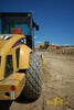 Tahačový válec Caterpillar CS-583E, v pozadí grejdr New Holland F156.6A