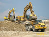 Pásové rypadlo Caterpillar 365C LME nakládá dempr Caterpillar 740, v pozadí rypadlo New Holland Kobelco E 385