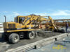 Kolové rypadlo Caterpillar 206B FT firmy Skanska DS rozhrnuje beton před finišerem