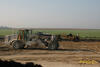 Půdní fréza Caterpillar RM 500, v pozadí Skrejpr Caterpillar 627F