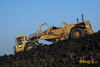 Skrejpr Caterpillar 627F vykládá materiál