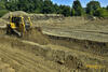 Dozer Caterpillar D6L XR shrnuje pruhy zeminy s pojivem po zemní fréze do hloubky 0,5 m