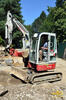 Strojník demonstruje skladnost hydraulického ramene pásového bagru Takeuchi TB 138 FR
