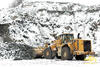 Kolový nakladač Caterpillar 988H s ochrannými řetězy Pewag Square Granit 18 u stěny