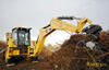Traktorbagr Caterpillar 432F nabírá klestí
