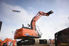 Pásové rypadlo Hitachi Zaxis ZX210XLC-6, v pozadí vzducholoď Zeppelin