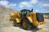 Kolový nakladač Caterpillar 966M XE vysýpá kamenivo z lopaty